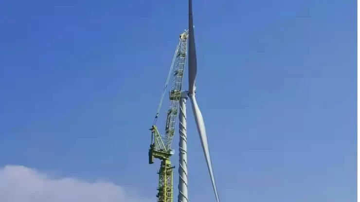 Wind turbine tower crane lifting a turbine equipment blade